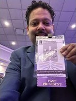 Kristian Bainey wearing a Past President badge at a professional event